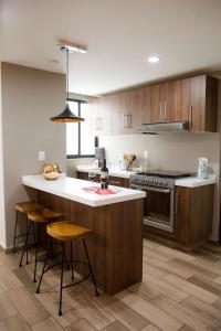 a kitchen with wooden cabinets and a kitchen island with stools at Kolben Nuoma in Mexico City