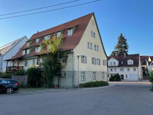 a large white building with a brown roof at 4 Betten in 3-Zimmer-Wohnung mit WLAN TV und Garten in Schwieberdingen