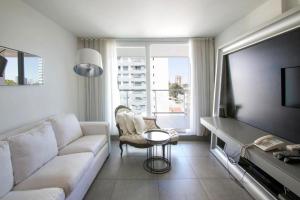 Yoo Punta Del Este في بونتا دل إستي: غرفة معيشة مع أريكة بيضاء وتلفزيون