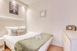 a small bedroom with a white bed and a clock at Loft proche PARIS SAINT-LAZARE in Courbevoie