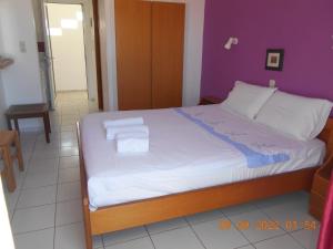 a bedroom with a large bed with a purple wall at Garifalia Studios in Kalamaki Heraklion