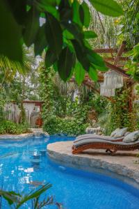 a pool with chaise lounges next to a resort at Hotel Hulku in Playa del Carmen