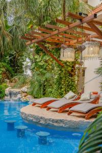 a group of lounge chairs sitting next to a swimming pool at Hotel Hulku in Playa del Carmen