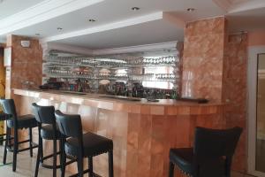 a bar with black chairs and a wooden counter at Hotel Impérial in Libreville