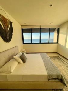 Cette chambre comprend un grand lit et une grande fenêtre. dans l'établissement Incredible Ocean View Penthouse with private pool by Baleine Group, à Holbox