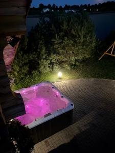 a hot tub with pink lighting on the side of a house at Privatus rąstinis namas su pirtimi in Dėckiai