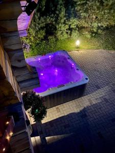 a purple hot tub in a backyard at night at Privatus rąstinis namas su pirtimi in Dėckiai