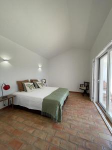 a bedroom with a bed and a large window at Corvatos Casas do Monte in Almodôvar +52 photos