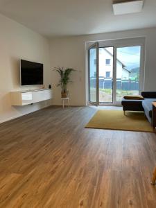 an empty living room with wooden floors and a flat screen tv at Ferienwohnung Gerstenecker in Hausen am Tann