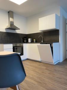 a kitchen with white cabinets and a table and a chair at Ferienwohnung Gerstenecker in Hausen am Tann