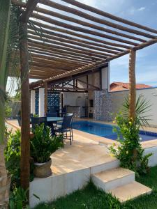 eine Terrasse mit Tisch und Stühlen unter einer Pergola in der Unterkunft Chalé Estrela da Barra in Barra Grande