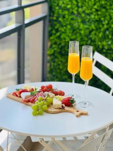 two glasses of orange juice and fruit on a table at Nal'enzo Luxe Stays in Johannesburg