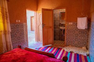 a bedroom with a bed and a bathroom with a shower at Maison etoile du desert in Tighmert