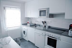 cocina blanca con fregadero y lavavajillas en Zubia Home Portugalete - Impecable- 3 min metro Bilbao, en Portugalete