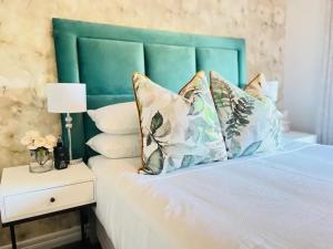 a bed with a green headboard and pillows on it at Nal'enzo Luxe Stays in Johannesburg