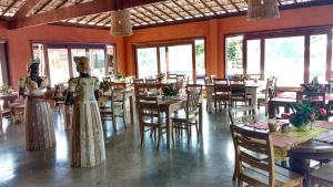 two women in dresses standing in a restaurant with tables at Villas do Pratagy Jambo I com Jacuzzy in Maceió