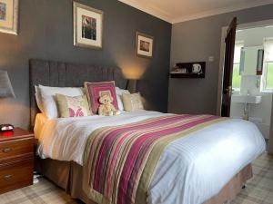 a bedroom with a large bed with a teddy bear on it at Gowanlea Guest House in Balloch