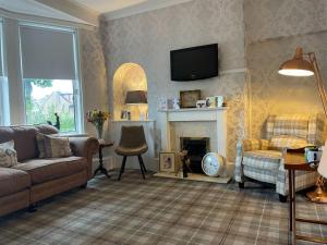 a living room with a couch and a fireplace at Gowanlea Guest House in Balloch