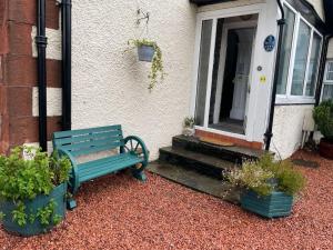 un banc vert assis devant une maison dans l'établissement Gowanlea Guest House, à Balloch