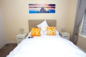 una camera da letto con un letto bianco e cuscini arancioni di Luxury Hot Tub - Entertainment Room - Near Central Park! a Peterborough