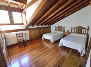 two beds in a room with wooden floors and windows at La Huertona in Pesaguero-La Parte