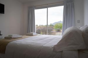 a bedroom with a large bed with a large window at Hotel Cantera Respira Campo in Potrero de los Funes