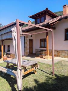 a wooden picnic table in front of a house at La Huertona in Pesaguero-La Parte