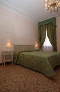 1 dormitorio con 1 cama con edredón verde y ventana en Casa Mimma, en Venecia