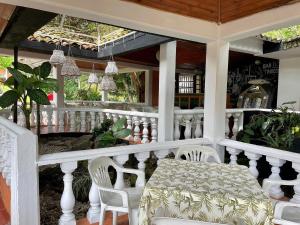 un porche blanco con mesa y sillas. en Hotel Hacienda El Diamante, en Villeta