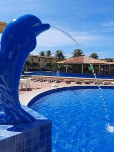 uma estátua de golfinho ao lado de uma piscina com uma fonte em Quarto139 Portobello Park em Porto Seguro