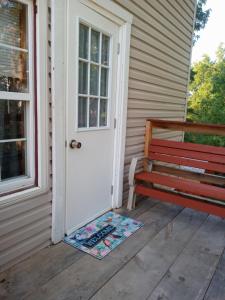 a porch with a red bench and a white door at Studio Apartment in Lake George Area. Near Vermont in Granville