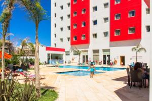 Una bambina in piedi di fronte alla piscina di un hotel di Ramada Encore By Wyndham Tangier a Tangeri