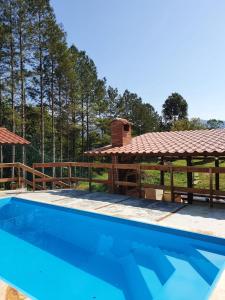 a swimming pool in front of a house with a pavilion at Hospedagem Rural Fazenda Sacramento in Rodeio Doze