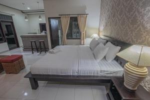 a bedroom with a large white bed and a table at Panorama Cottages I in Legian