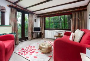 ein Wohnzimmer mit 2 roten Stühlen und einem TV in der Unterkunft Low Tarn Lodge in Elterwater