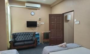 een kamer met een bank, een tv en een stoel bij NZ Villa Roomstay in Kangar
