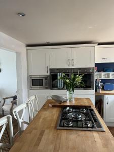 a kitchen with white cabinets and a table with a stove at Sea Facing 2BD Terraced Home - Peacehaven in Peacehaven