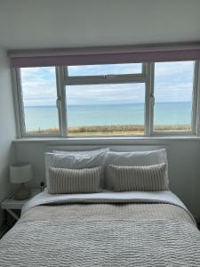 a bedroom with a bed and a large window at Sea Facing 2BD Terraced Home - Peacehaven in Peacehaven