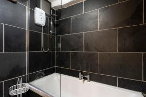 a bath tub in a bathroom with black tiles at Jontys Cottage in Ambleside +13 photos