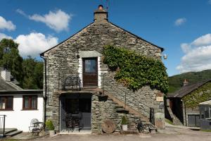 a small stone building with a window and stairs at Jontys Cottage in Ambleside
