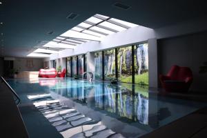 a lobby with a swimming pool with a red chair at Palace Hotel & SPA in Mitrovicë