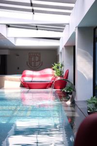 - une piscine avec un canapé rouge et un fauteuil rouge dans l'établissement Palace Hotel & SPA, à Kosovska Mitrovica