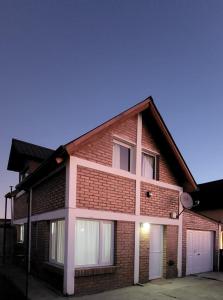 a brown brick house with two white garage doors at Valle Florido 2 in Trevelin