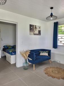 a living room with a blue couch and a bed at les tiny houses d'akapa in Sainte-Luce
