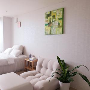 Cozy - Good Vibes Studio في انشيون: غرفة معيشة مع أريكة ولوحة على الحائط