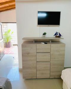 telewizor na drewnianej komodzie w sypialni w obiekcie Casa campestre los cerezos w mieście Santa Marta