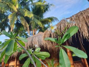 a thatched hut with palm trees in front of it at SAME SAME Bungalows by The Spot in Kuta Lombok