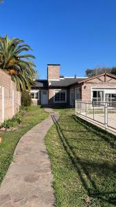 una pasarela frente a una casa con una palmera en Los abuelos en San Antonio de Areco