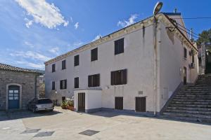 a white building with a car parked in front of it at Apartments by the sea Veli Losinj, Losinj - 19782 in Veli Lošinj