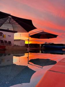 ein Pool mit zwei Sonnenschirmen im Wasser bei Sonnenuntergang in der Unterkunft Bargara Blue Resort in Bargara
